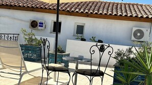 An outdoor patio with a table and chairs, surrounded by potted plants and a large umbrella. - Room Sidi bou Said (Hergla)