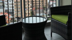A balcony with wicker furniture and a view of a cityscape.