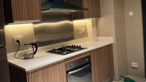 A modern kitchen with a gas stove, oven, and a kettle on the counter.