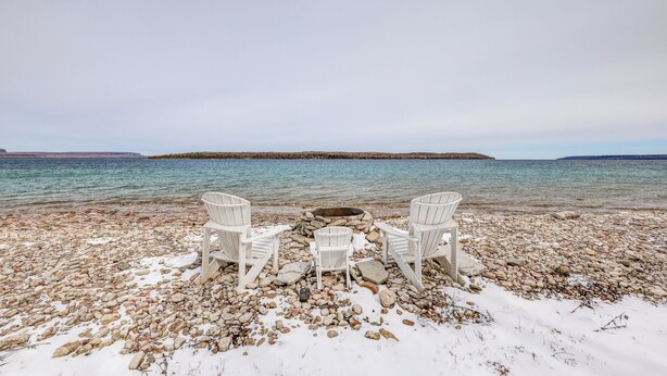 A rocky beach with two white chairs and a fire pit. - Cozy cottage nestled along 90ft of pristine Georgian Bay pebble beachfront (Wiarton)