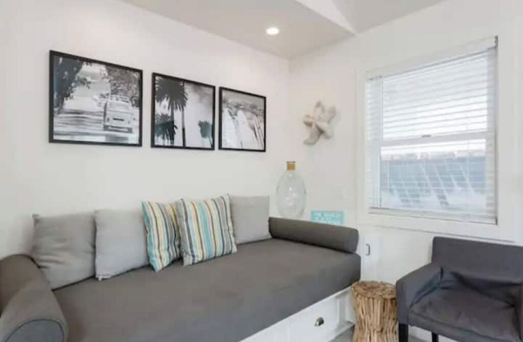 Ein modernes Wohnzimmer mit einem grauen Sofa, gestreiften Kissen und schwarz-weißen gerahmten Bildern an der Wand.