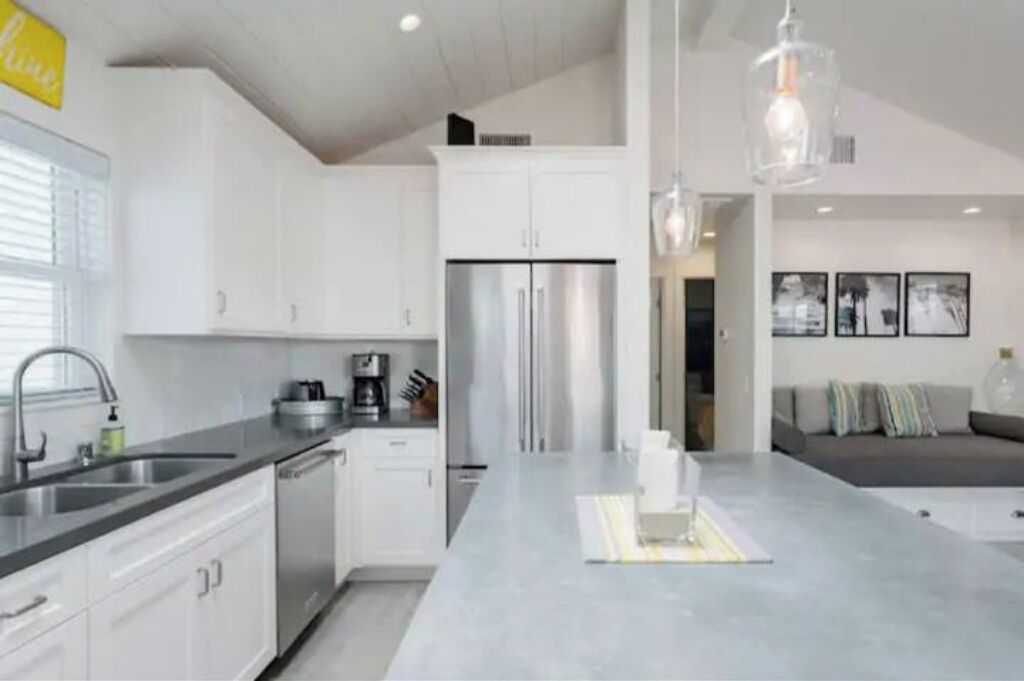 A modern kitchen with white cabinets, a stainless steel refrigerator, and a central island.