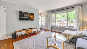Ein modernes Wohnzimmer mit großem Fenster, Flachbildfernseher, Sofa und Glastisch.