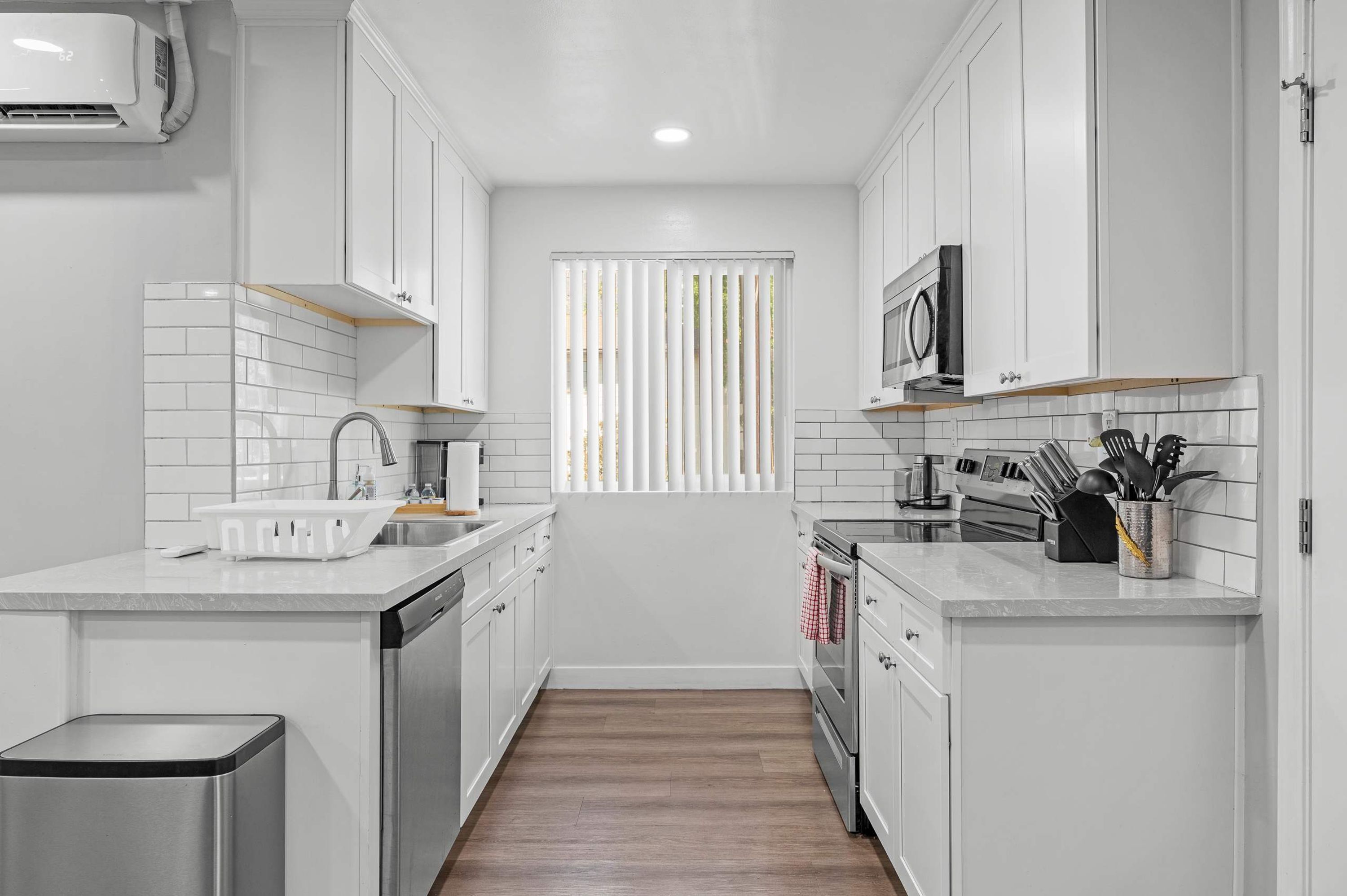 A modern kitchen with white cabinets, a microwave, and a sink.
