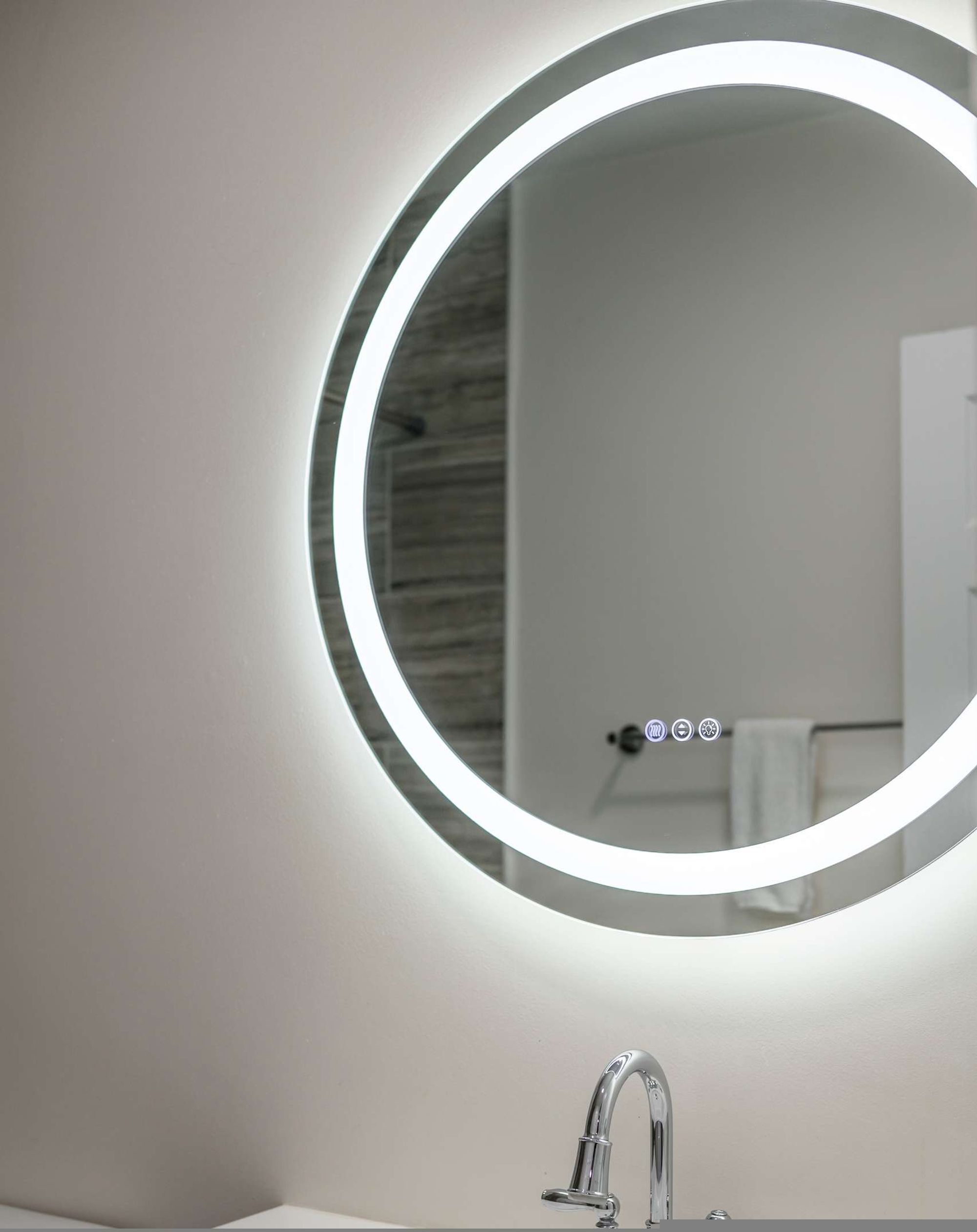A bathroom with a round mirror, a modern faucet, and a towel rack.