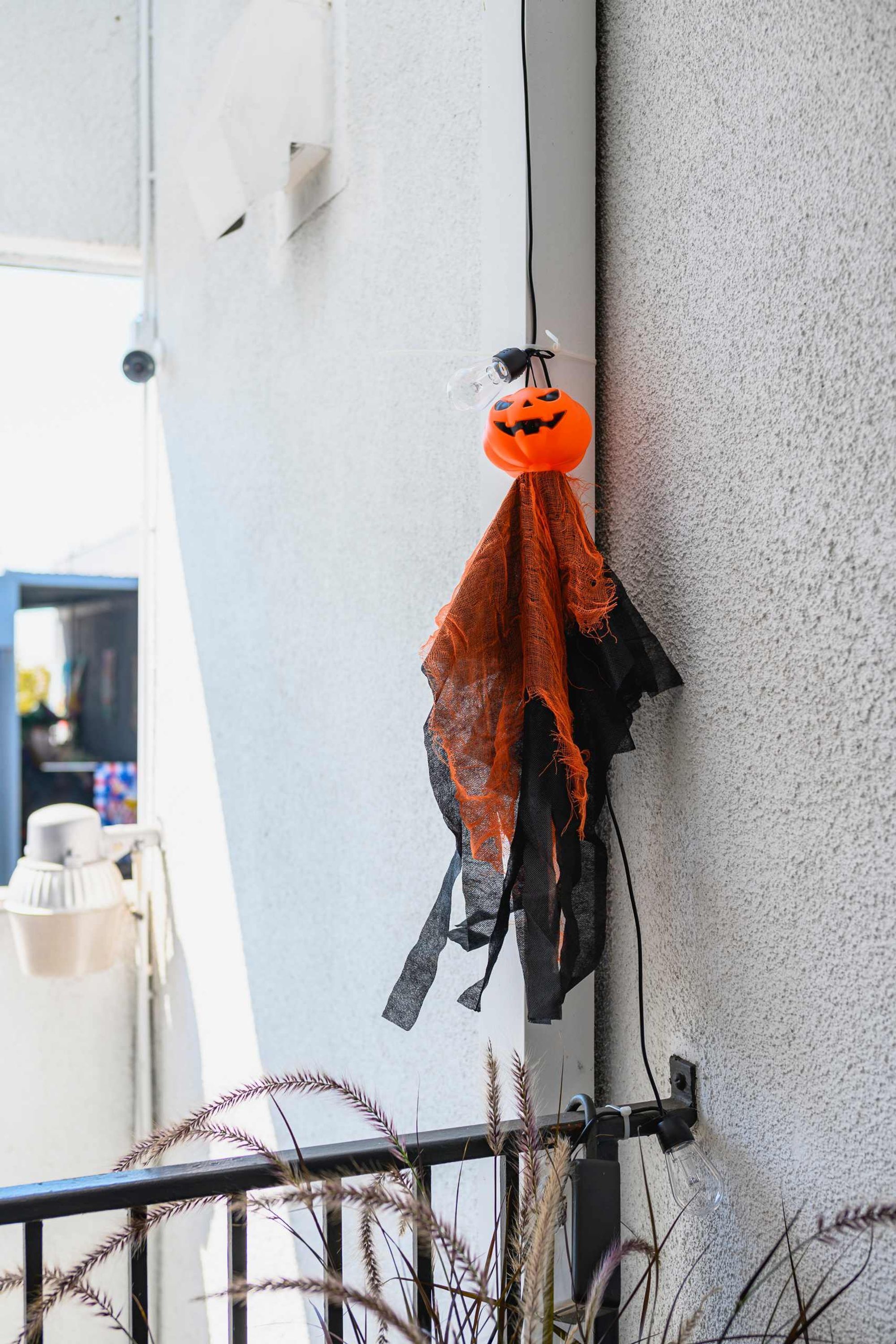 Halloween-koriste, jossa on kurpitsa ja seinälle ripustettu hämähäkki.