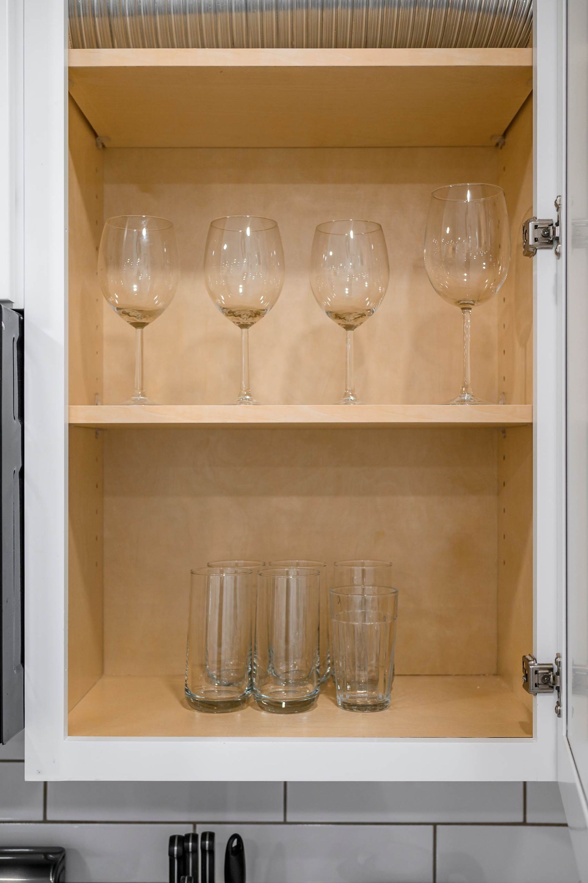 Un meuble de cuisine doté de deux étagères : l’une pour quatre verres à vin et l’autre pour quatre verres ordinaires.