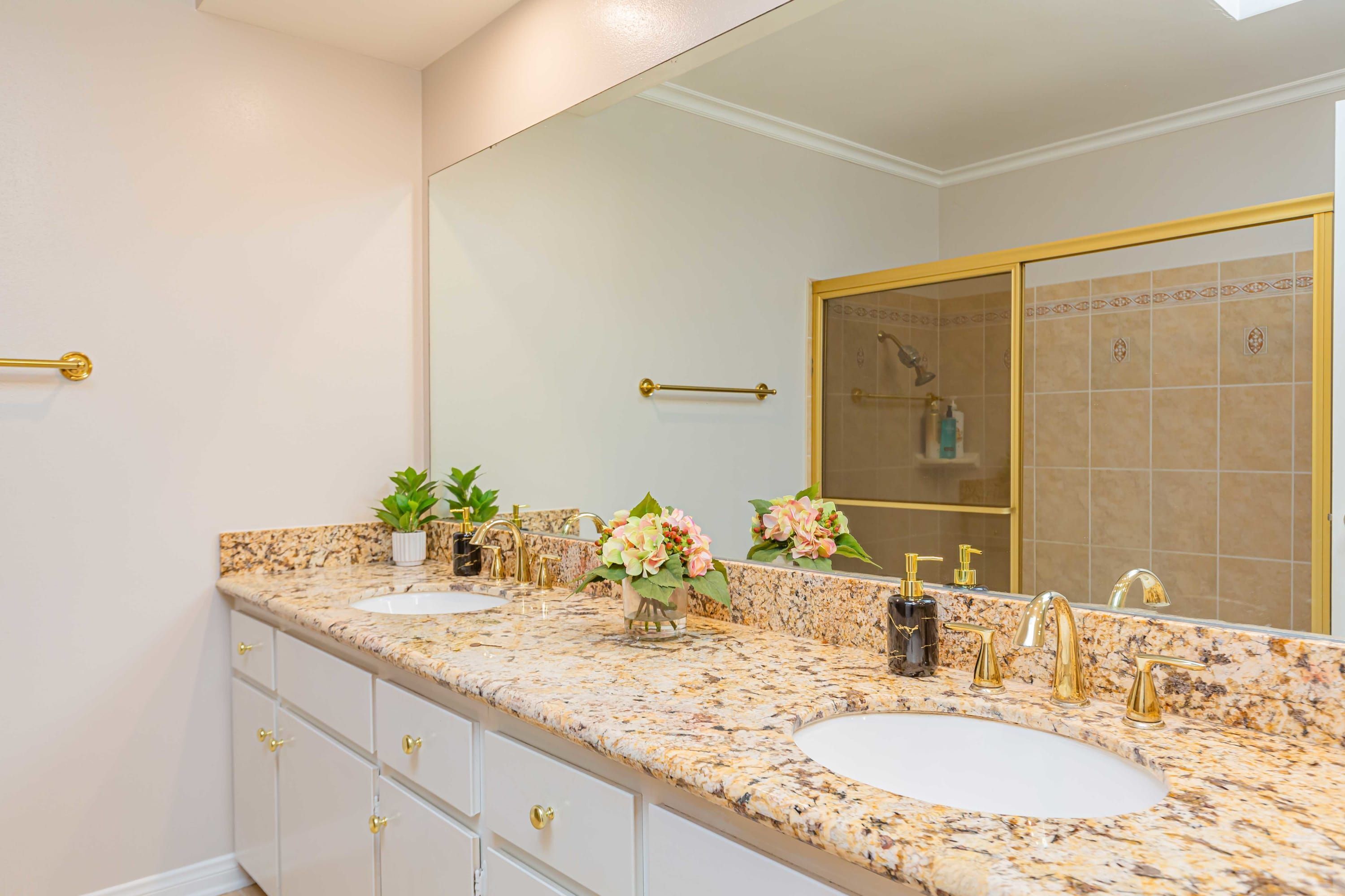 Un baño con dos lavamanos, un espejo grande y zona de ducha.