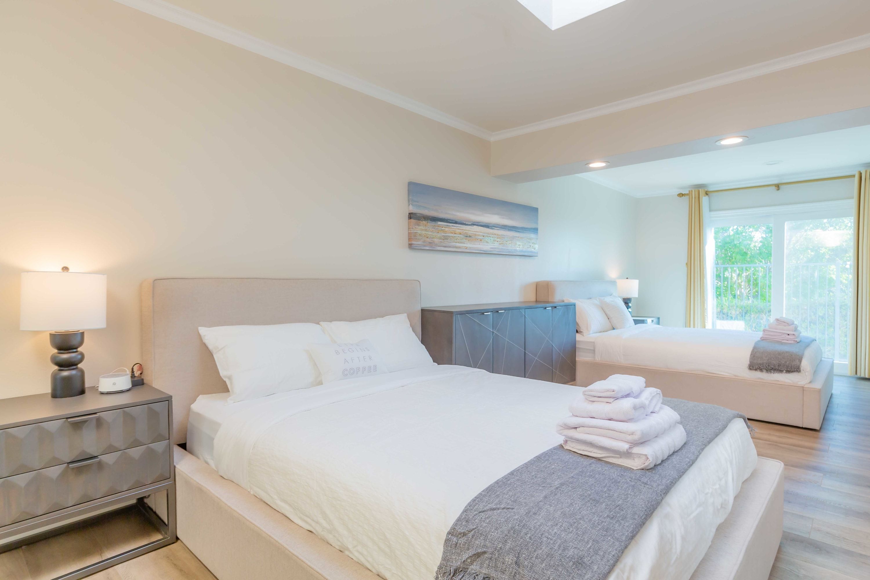 Une chambre à coucher moderne avec un grand lit, une table de chevet, une commode et un tableau au mur.