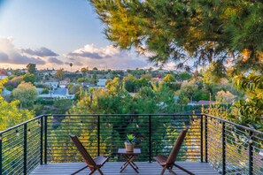 A balcony with two wooden chairs and a small table, overlooking a residential area with houses and trees. - Stunning LA Luxury Retreat Ideal for Work or Play (Monterey Park)