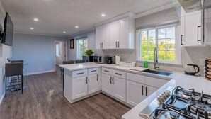 A modern kitchen with white cabinets, a built-in stove, and a large window providing natural light. - Stunning LA Luxury Retreat Ideal for Work or Play (Monterey Park)