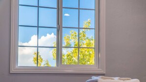 A window with a view of trees and sky, a white wall, and a bed with a patterned blanket. - Stunning LA Luxury Retreat Ideal for Work or Play (Monterey Park)