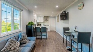A modern kitchen with a central island, a dining area with a glass table, and a sofa with patterned cushions. - Stunning LA Luxury Retreat Ideal for Work or Play (Monterey Park)