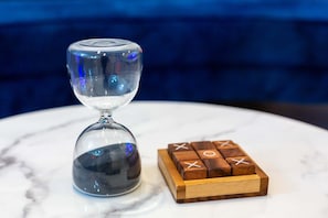 A clear glass hourglass and wooden tic-tac-toe game on a marble surface. - Elegant Pasadena Retreat Prime Comfort Awaits (Pasadena)
