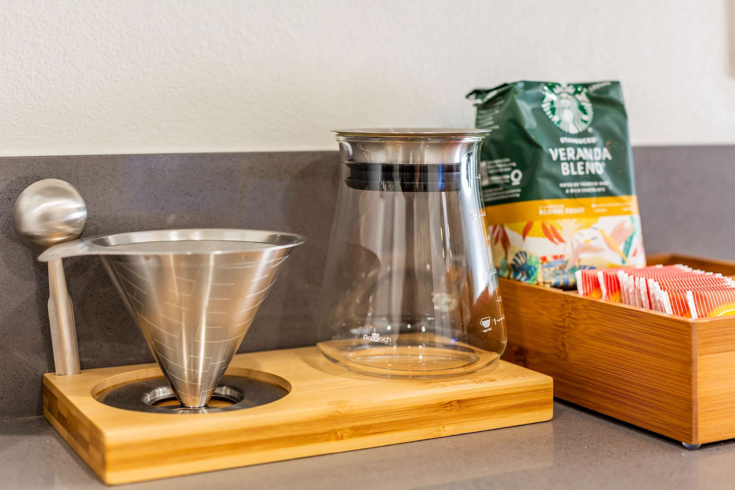 A coffee maker, a bag of coffee, and a box of coffee capsules on a countertop.