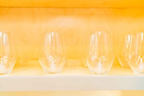 A row of empty wine glasses on a white shelf against a yellow background. - Elegant Comfort on Historic Route 66 Attractions (Glendora)