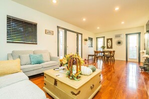 A living room with a sofa, a wooden chest, and a dining area with chairs and a table. - Elegant Comfort on Historic Route 66 Attractions (Glendora)
