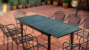 An outdoor patio with a rectangular table and six chairs, surrounded by potted plants and a wooden fence. - Cozy Family Retreat Game Room Backyard in Hacienda (Hacienda Heights)