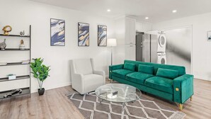 A modern living room with a green sofa, a white armchair, a glass coffee table, and a potted plant. - Newly Remodeled 2b2b APT Near Pasadena Old Town (Altadena)