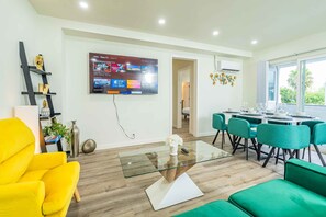A modern living room with a glass coffee table, a yellow armchair, and a dining area with teal chairs and a white table. - Newly Remodeled 2b2b APT Near Pasadena Old Town (Altadena)