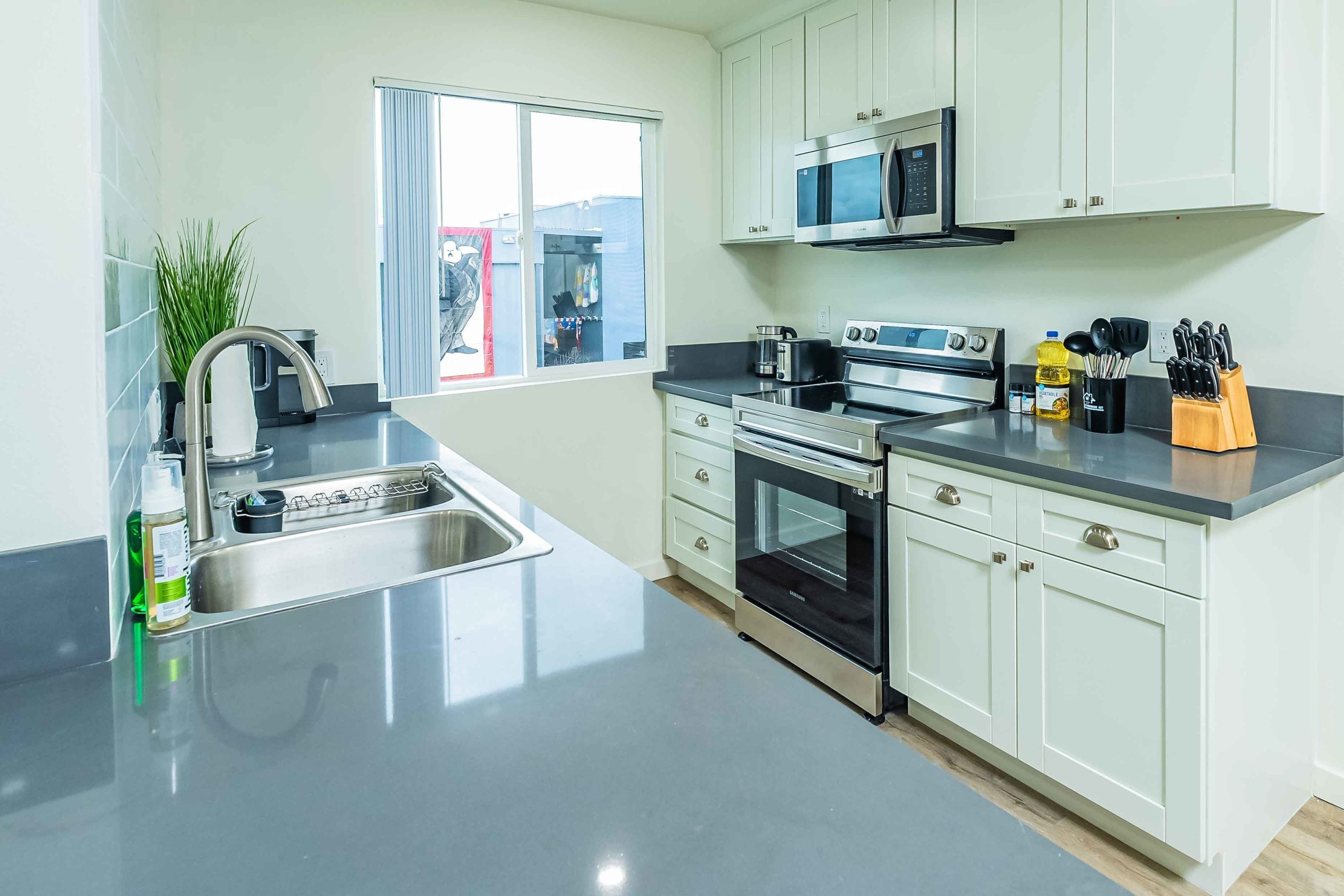 A modern kitchen with stainless steel appliances, a sink, and a window with a view of the outside.