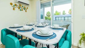 A dining area with a white table set for four, teal chairs, and a decorative wall piece. - Newly Remodeled 2b2b APT Near Pasadena Old Town (Altadena)