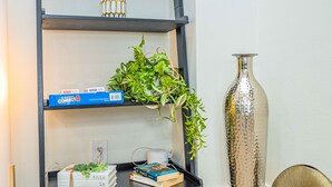A black metal shelf with a plant, a box labeled "CONNECT4," and books. - Newly Remodeled 2b2b APT Near Pasadena Old Town (Altadena)