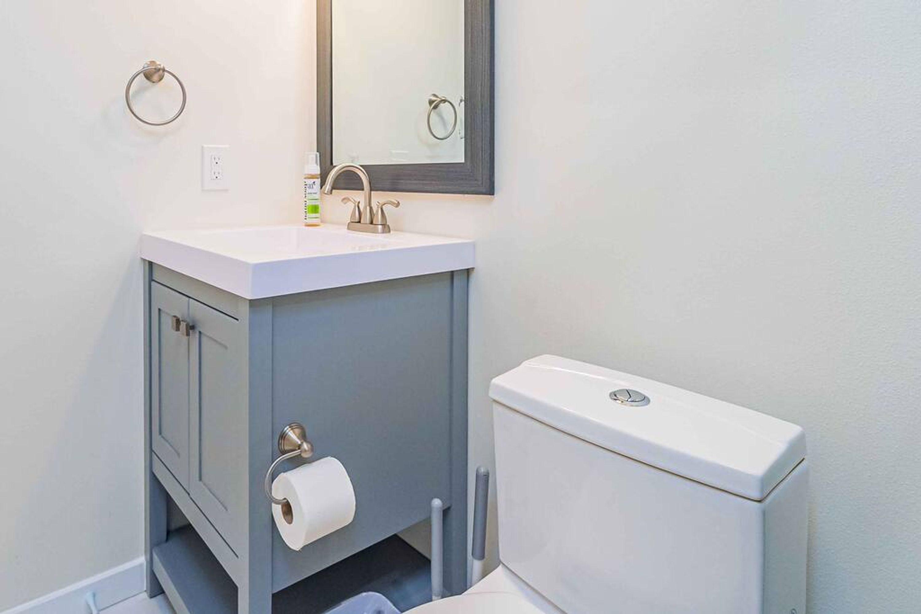 A bathroom with a white sink, a mirror, a toilet, and a towel ring.