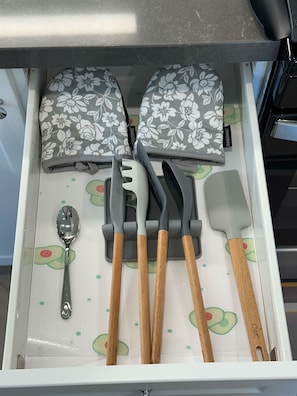 Un cajón con utensilios de cocina, incluyendo una cuchara, espátulas y un rallador.