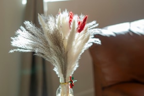 Un jarrón con plumas blancas y rojas, atado con un lazo verde y rojo.