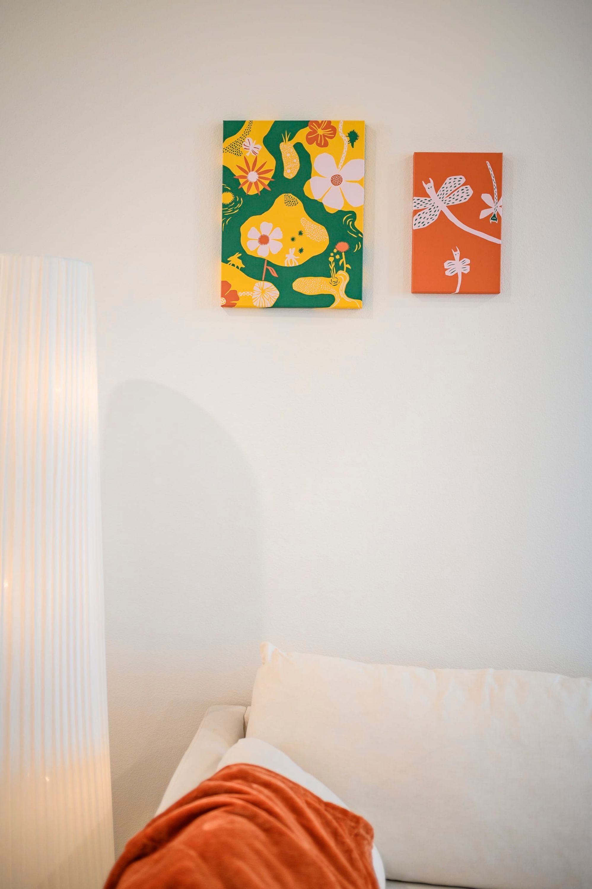 Una stanza con un letto, una lampada e due opere d'arte appese al muro.