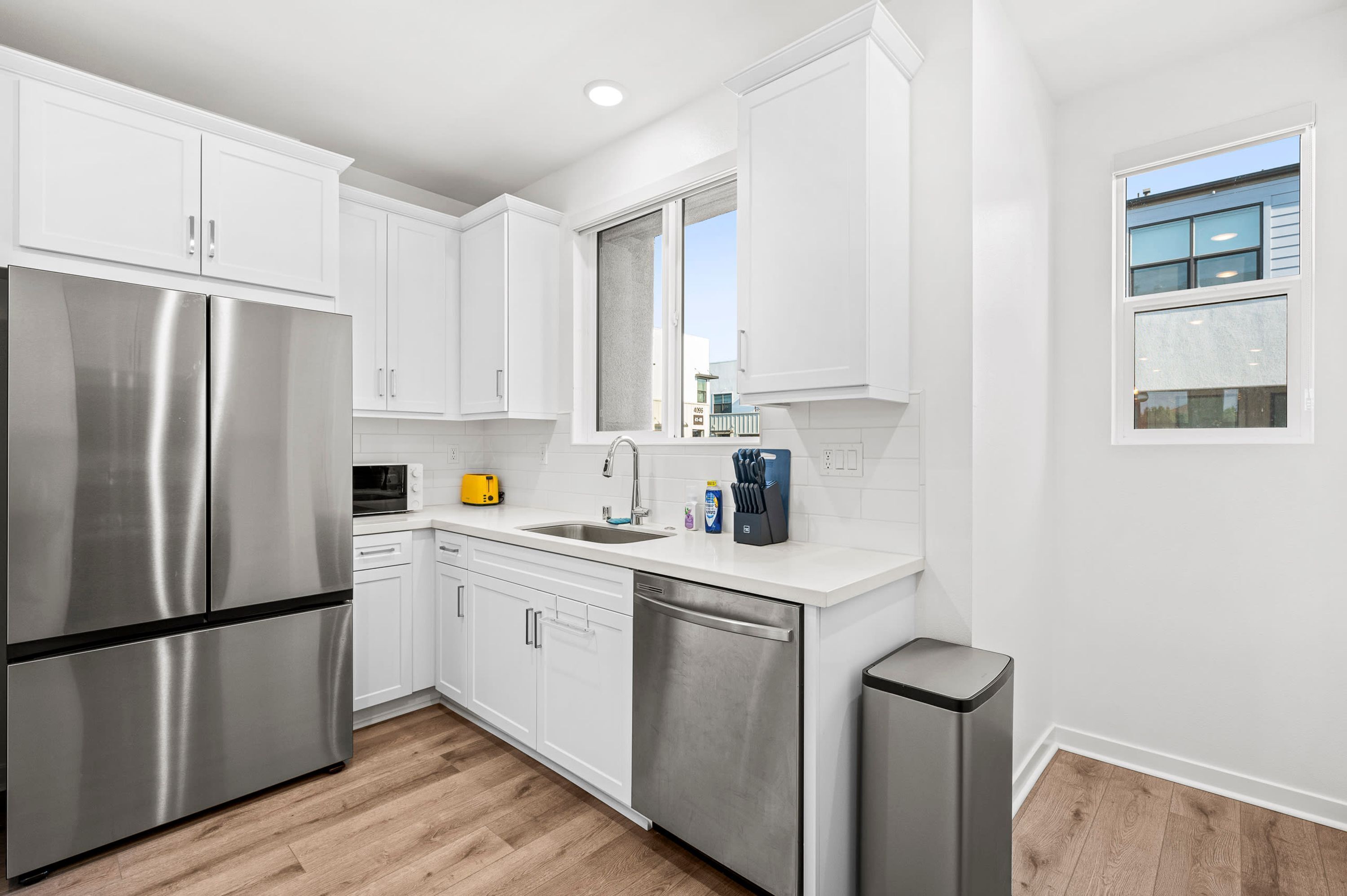 A modern kitchen with stainless steel appliances, white cabinetry, and a window providing natural light.