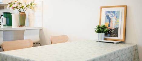 A dining area with a marble table, chairs, a vase with flowers, a framed picture, and a sign on the wall.