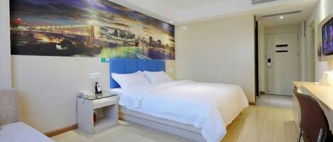 Una habitación de hotel con cama, escritorio, silla, mesita de noche y televisión montada en la pared.