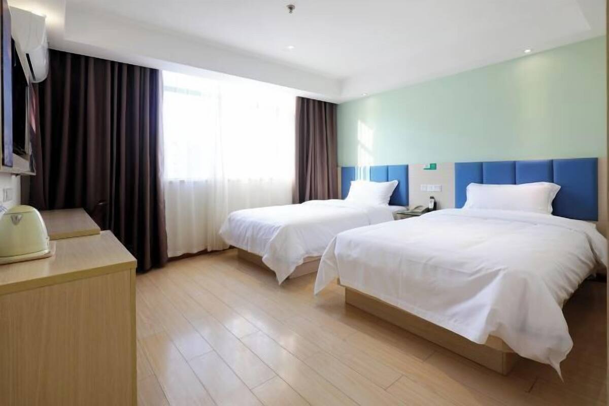 Una habitación de hotel con dos camas, un escritorio y una televisión.