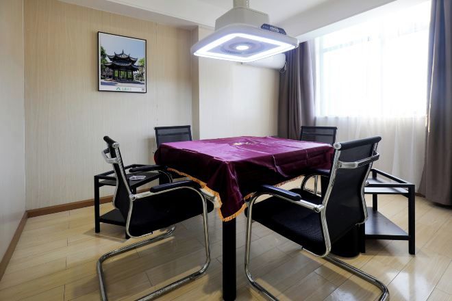 A dining area with a table covered by a purple tablecloth, surrounded by four black chairs with metal frames. A modern pendant light hangs above the table.