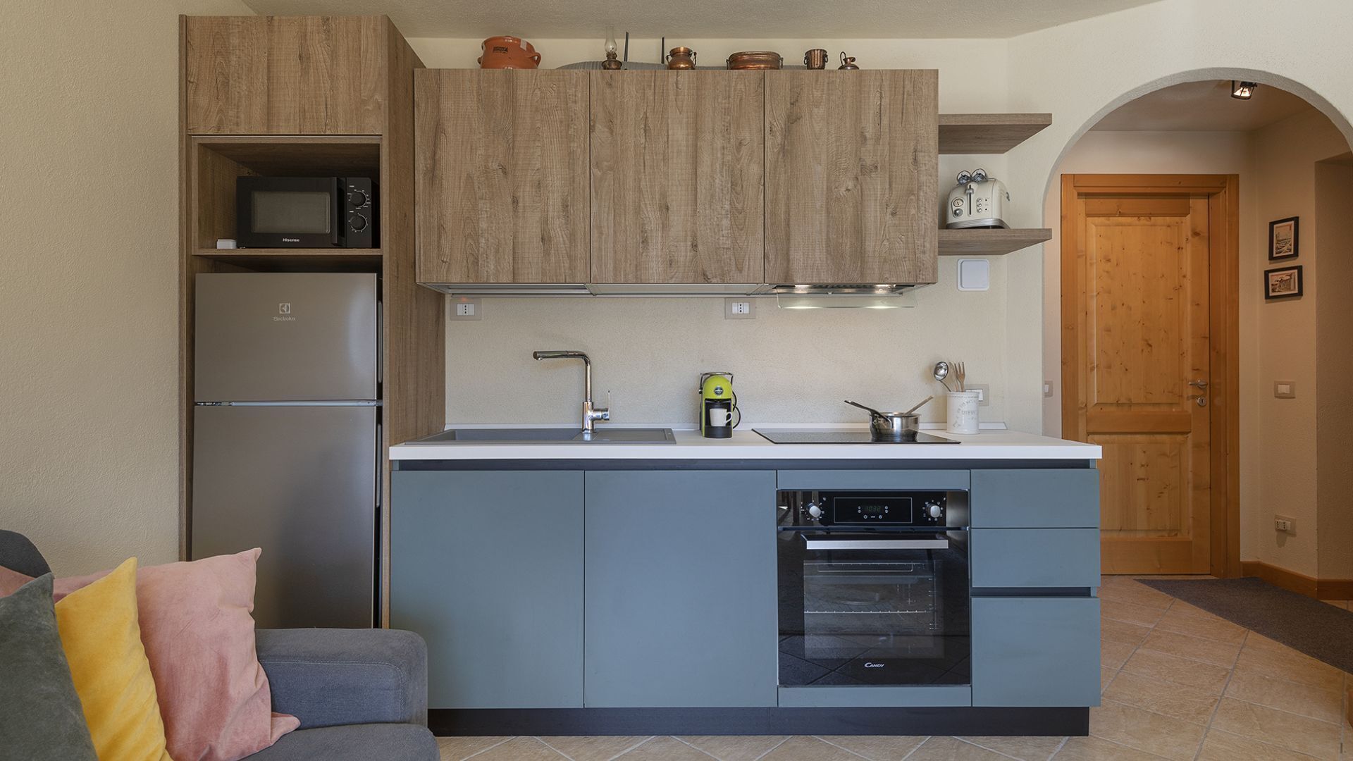 A compact kitchen with wooden cabinets, a built-in microwave, a coffee maker, and a dishwasher.