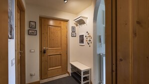 A hallway with a wooden door, a small white table, and wall-mounted decorations.