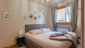 A bedroom with a bed, bedside tables, a lamp, and framed pictures on the wall.