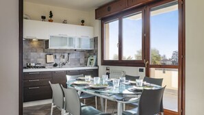 A modern kitchen with dark cabinets, a gas stove, and a dining area with a glass table and chairs. - The House on the Lake (Reno)