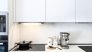 Une cuisine équipée d’une cuisinière, d’une machine à café et d’une casserole posée sur le plan de travail.