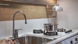 A modern kitchen with a stainless steel sink, a gas stove, and a wooden backsplash. - Sunshine - Two Bedroom Apartment, Sleeps 4 (Vione)