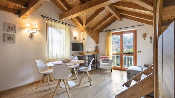 A cozy dining area with a wooden ceiling, a fireplace, and a TV mounted on the wall. - Sunshine - Two Bedroom Apartment, Sleeps 4 (Vione)