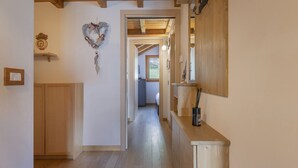 A narrow hallway with wooden flooring, a wooden door on the left, and a small shelf with a candle holder on the right. - Sunshine - Two Bedroom Apartment, Sleeps 4 (Vione)