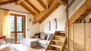 A cozy living room with a wooden staircase, a sofa with cushions, and a window with curtains. - Sunshine - Two Bedroom Apartment, Sleeps 4 (Vione)