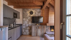 Une cuisine moderne avec un mur en pierre, un plafond en bois et une cheminée.