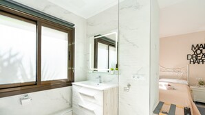 Une salle de bain moderne avec un meuble-lavabo en marbre, un grand miroir et une table de chevet.