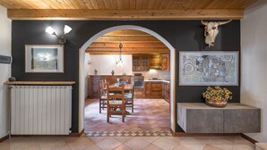 A rustic kitchen with wooden beams, a dining area with a herringbone floor, and a cow skull decoration. - Eden View - Two Bedroom Apartment, Sleeps 6 (Monno)
