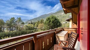 Un balcon en bois offrant une vue sur un lac et des montagnes.