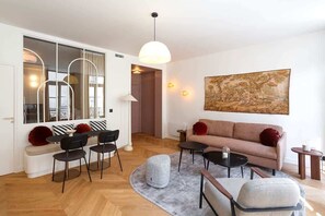 A modern living room with a sofa, chairs, a coffee table, and a large painting on the wall.